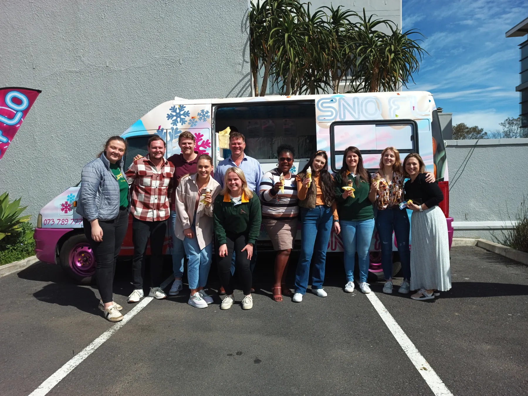 Office staff with ice creams in front of the SNO FLO bus