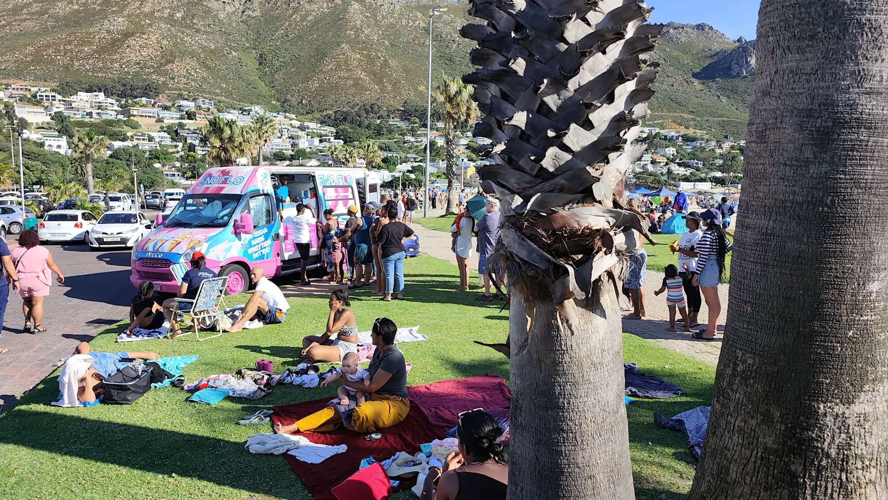 Families on the lawn at the SNO FLO bus with the mountains behind