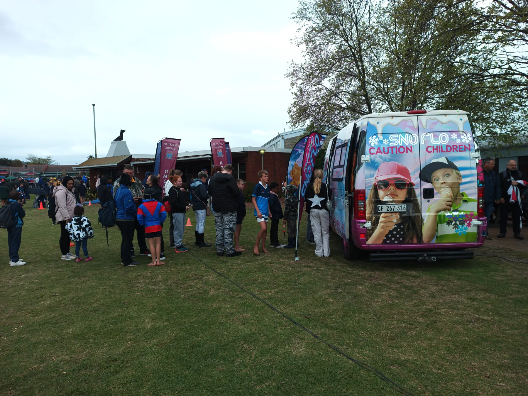 Learners queuing at the SNO FLO bus on a school field